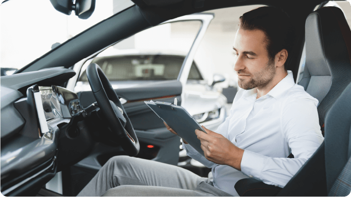 Salesman sitting inside a car, looking at a tablet