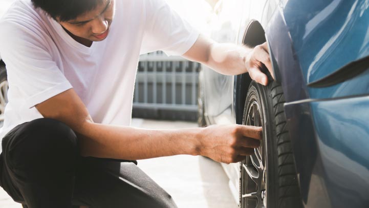 Car owner checking the condition of a tyre